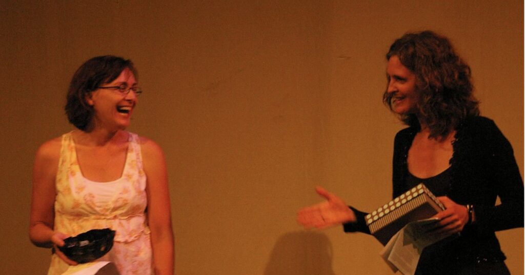 Founding Producers Rebecca Fisher and Bridget Frederick onstage together in an early Tell It On Tuesday live storytelling evening.